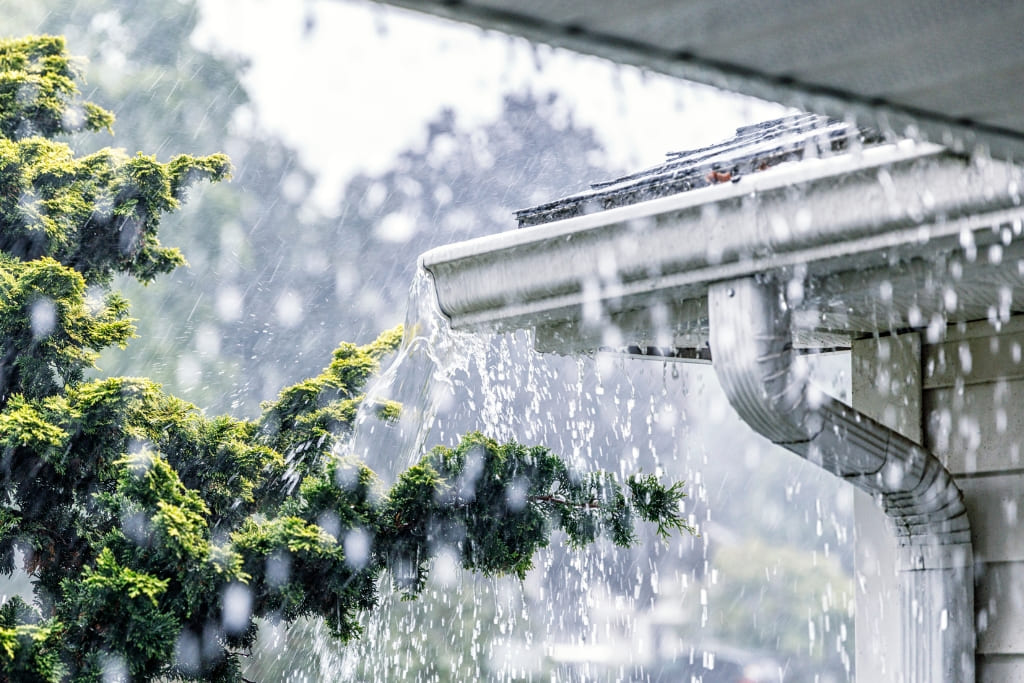 Heavy rainfall against a roof and tree